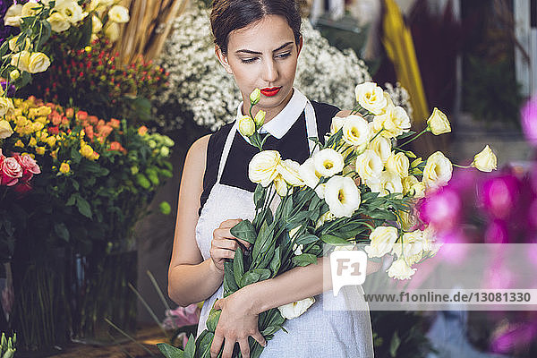 Female florist holding bunch of flowers in shop