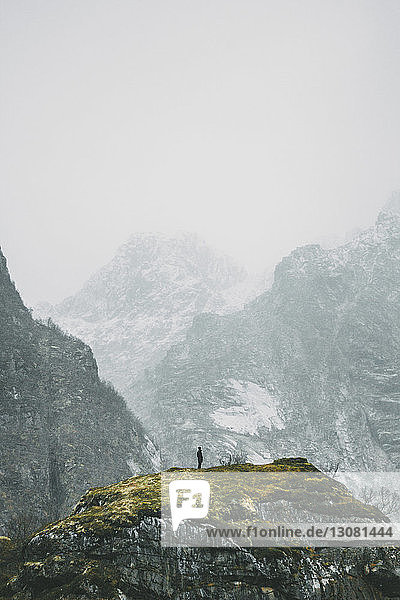 Fernsicht einer Person  die im Winter auf einem Berg steht