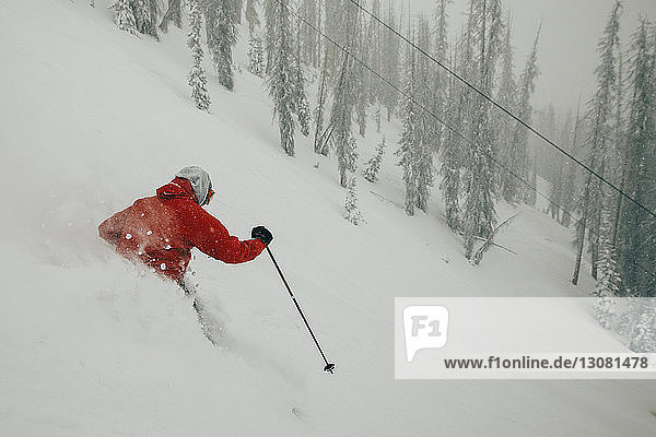 Hochwinkelaufnahme eines Mannes beim Skifahren auf einem schneebedeckten Berg