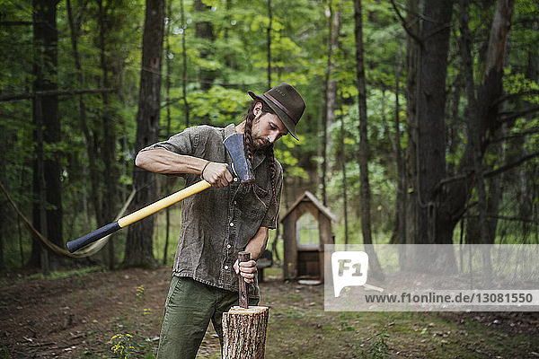 Mann schneidet Brennholz mit dem Hammer im Wald