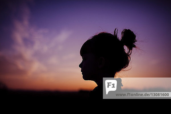 Silhouette girl against dramatic sky during sunset