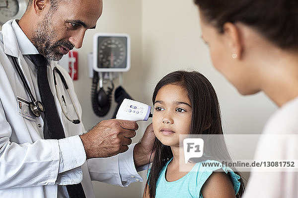 Mother looking at doctor checking daughter