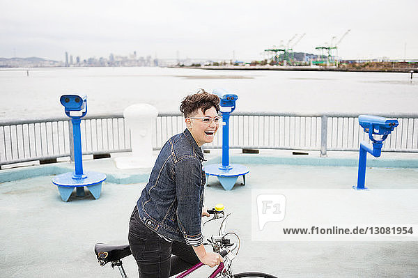 Fröhliche Frau fährt Fahrrad auf Wanderweg am Meer