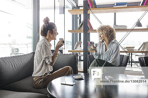 Happy businesswomen discussing while having coffee at cafe