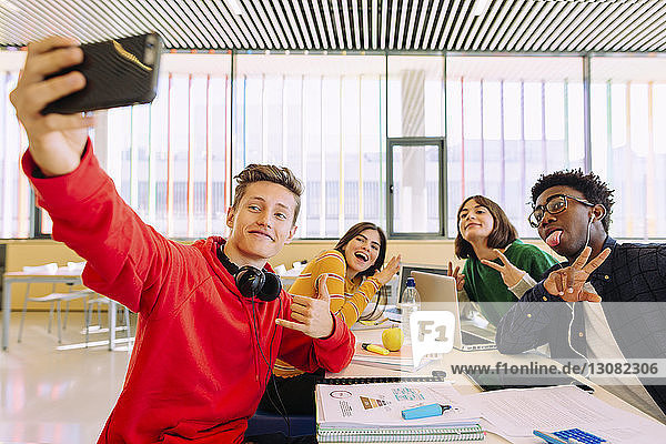 Man taking selfie with friends at table in library