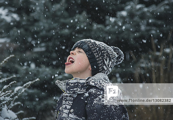 Verspielter Junge streckt bei Schneefall die Zunge heraus