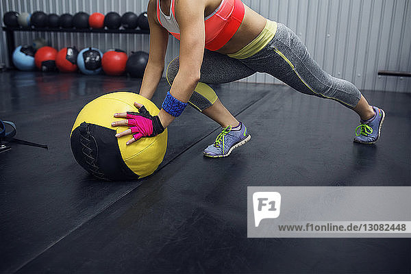 Niedriger Abschnitt einer Sportlerin  die sich im Fitnessstudio auf einen Medizinball stützt