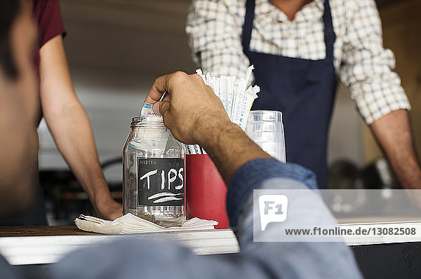 Close-up of customer putting tips in jar at food truck with vendors