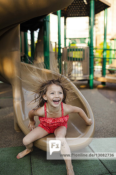 Happy girl playing on slide at playground