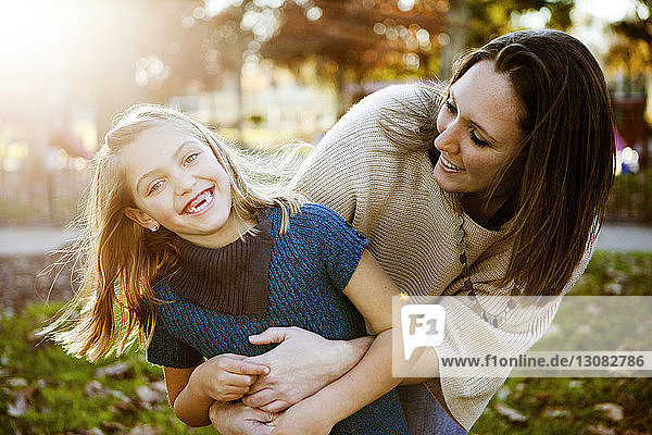 Cheerful mother playing with daughter at park during autumn