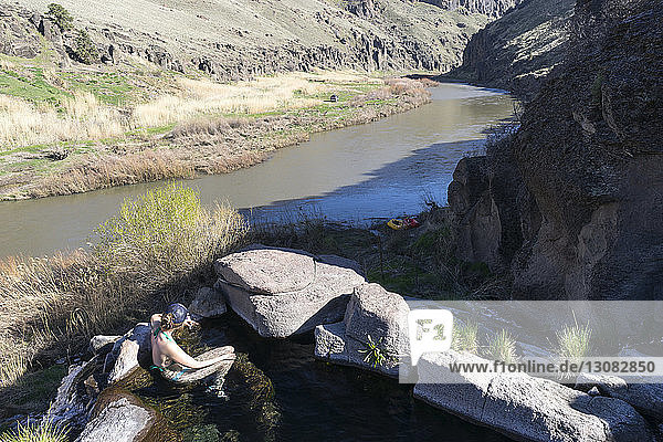High angle view of female hiker in hot spring during sunny day