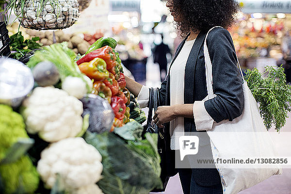 Seitenansicht einer Frau  die Gemüse auf dem Markt kauft