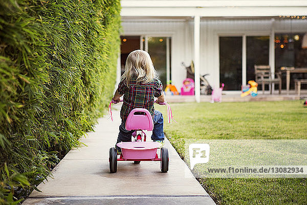 Rückansicht eines Mädchens auf einem Dreirad im Hof