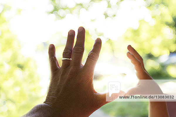 Vater und Kind berühren Finger gegen Sonnenlicht