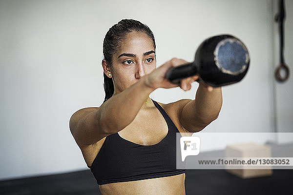 Female athlete exercising with kettlebell in crossfit gym