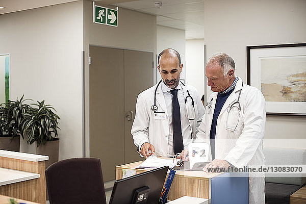 Doctors discussing medical reports while standing in hospital