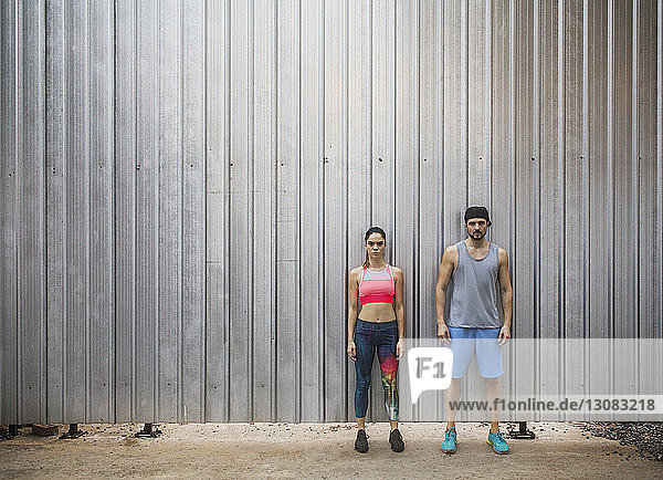 Serious couple standing against metal wall
