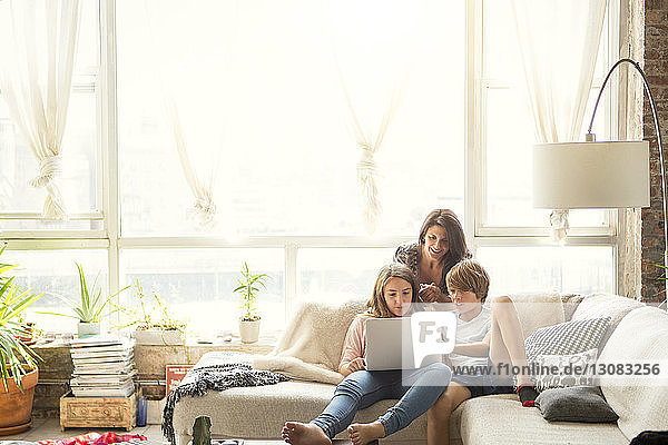 Mother looking at children using laptop computer