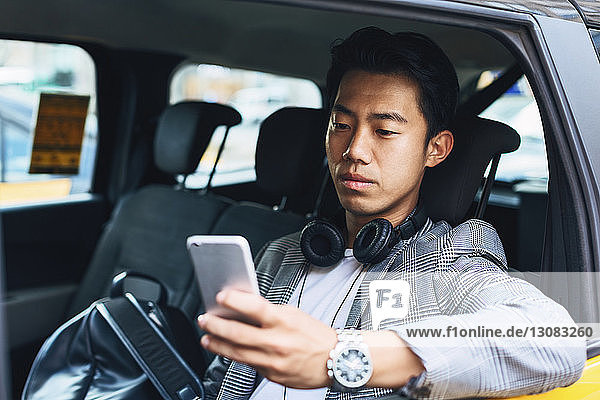Geschäftsmann benutzt Smartphone  während er im Taxi sitzt
