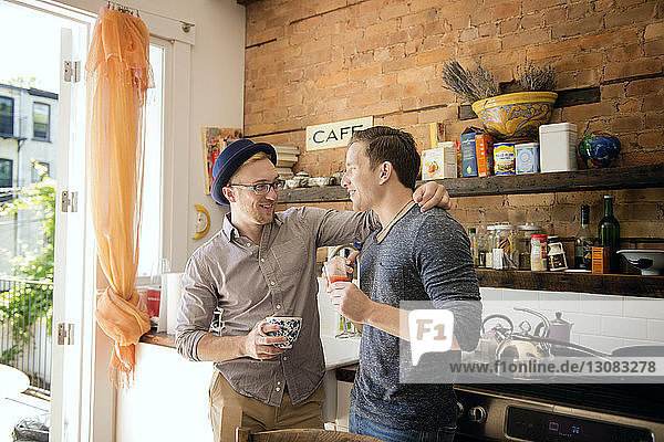Gay couple standing against kitchen counter at home