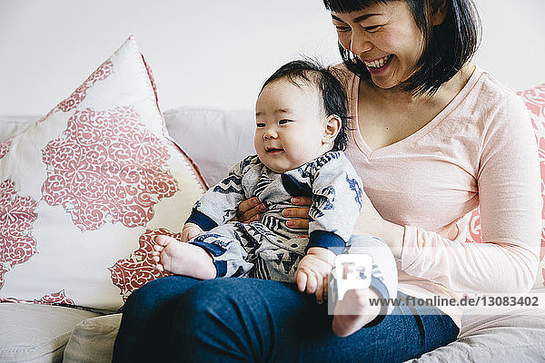 Happy mother with cute son sitting on sofa in living room