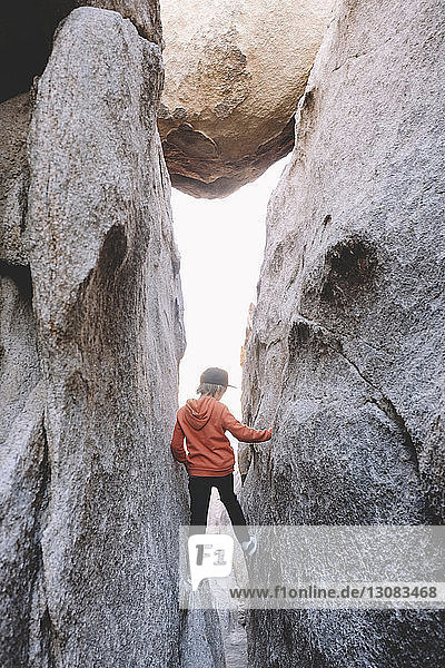 Rear view of boy standing amidst rock formations at Joshua Tree National Park