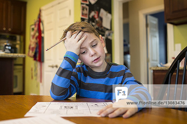 Boy studying by table at home