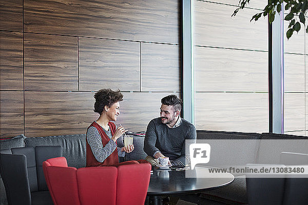 Cheerful business couple enjoying drinks while sitting in restaurant