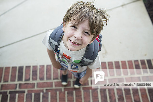Hochwinkelporträt eines Jungen mit Rucksack auf Stufen stehend