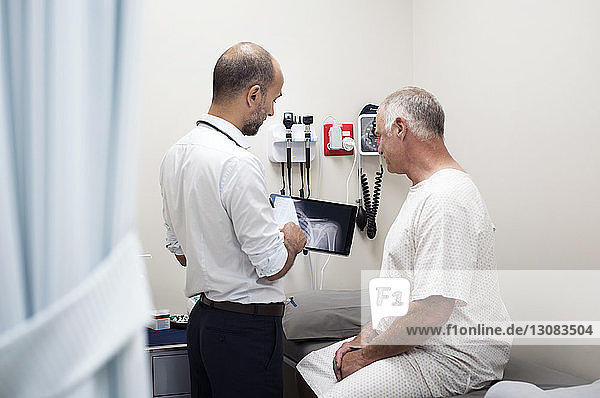 Doctor showing x-ray reports in tablet computer to patient at hospital