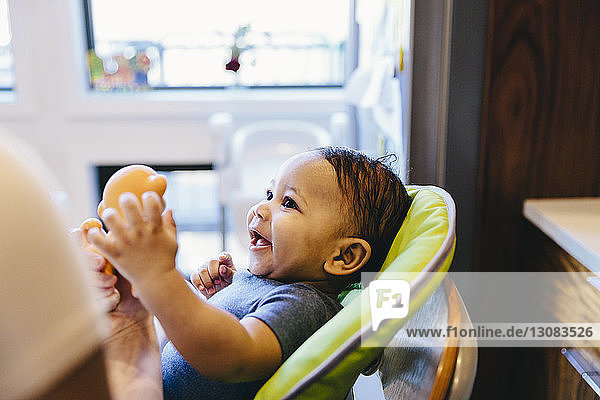 Close-up of happy boy sitting on high chair at home