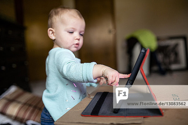 Hübsches Mädchen benutzt Tablet-Computer  während es zu Hause an der Kiste steht