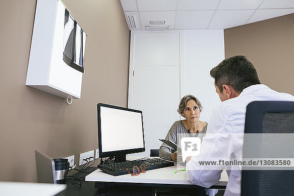 Close-up of doctor discussing with woman while sitting at hospital