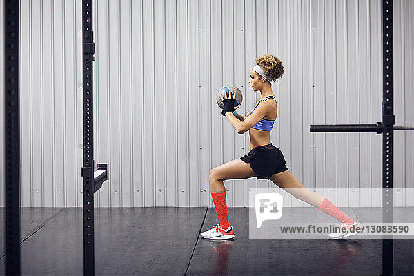 Determined female athlete exercising with medicine ball in gym