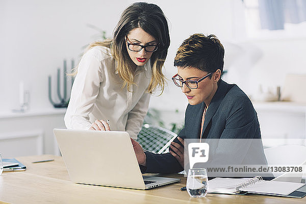 Geschäftsfrauen diskutieren  während sie im Büro einen Laptop benutzen