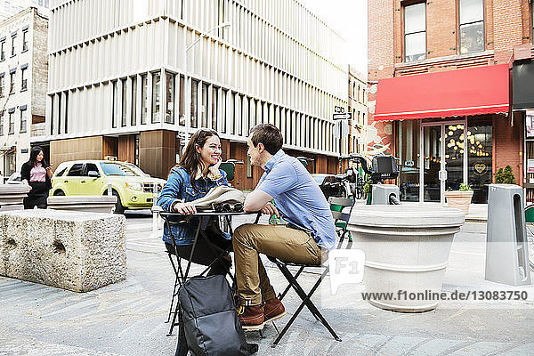 Ehepaar sitzt am Tisch an der Straße gegen Gebäude in der Stadt