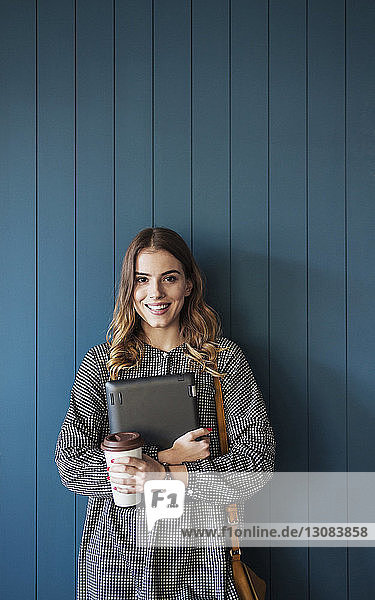 Portrait of smiling woman standing against wall in classroom
