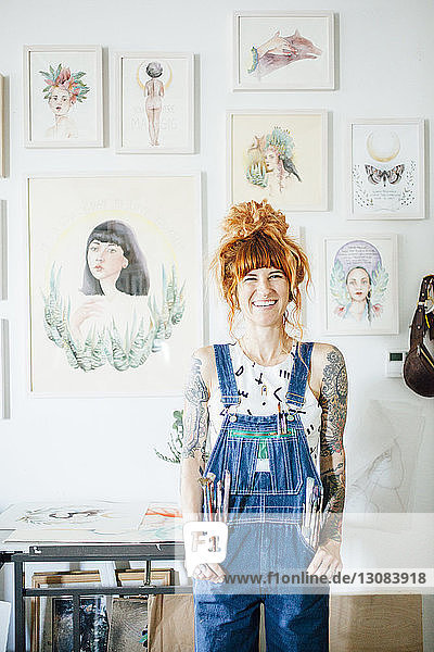 Porträt eines lächelnden Künstlers mit Händen in den Taschen im Atelier stehend