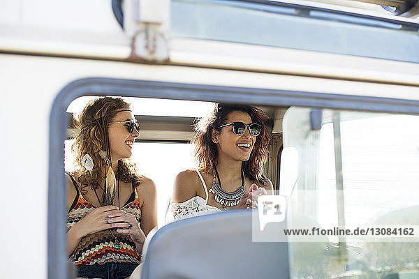 Happy friends sitting in off-road vehicle seen through window