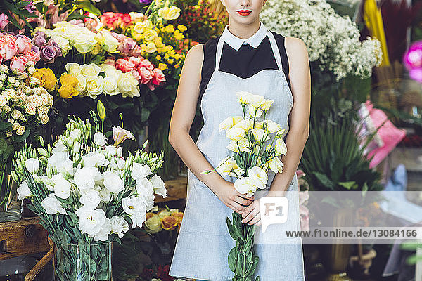 Midsection of florist holding yellow roses at shop