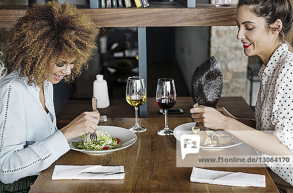 Happy businesswomen having lunch at table in restaurant