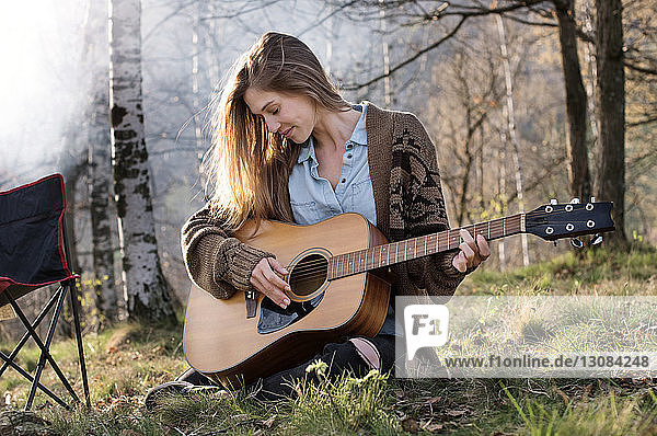 Schöne Frau spielt Gitarre im Wald