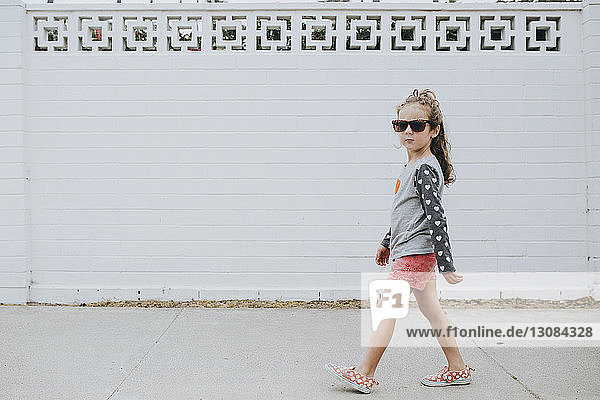 Mädchen mit Sonnenbrille geht auf Fußweg