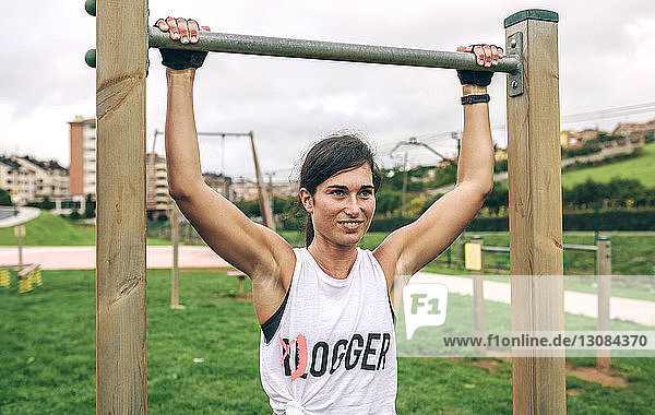 Selbstbewusste Frau hält Gymnastikbalken während des Trainings im Park