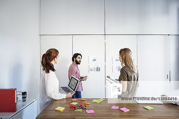 Businessman training female colleagues while standing in office