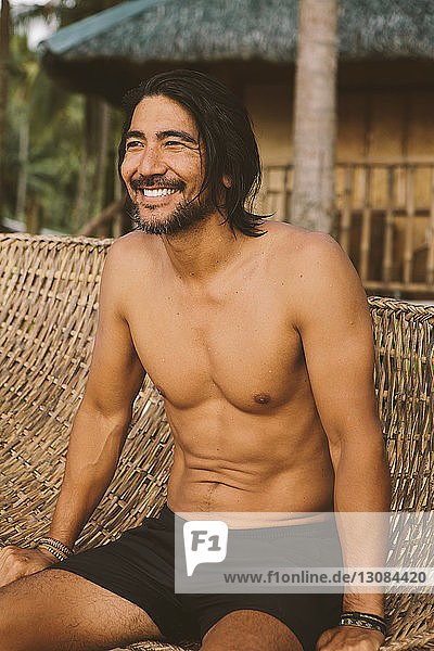 Mann ohne Hemd schaut weg  während er sich in der Hängematte am Strand entspannt