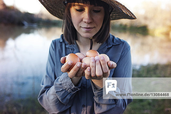 Junge Bäuerin hält Eier  während sie am Seeufer steht