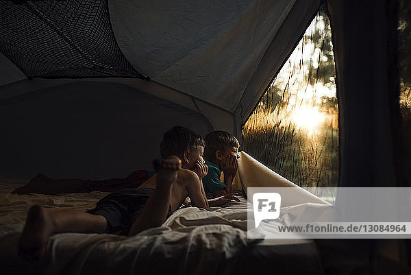 Nachdenkliche Brüder schauen durch das Fenster  während sie im Zelt liegen