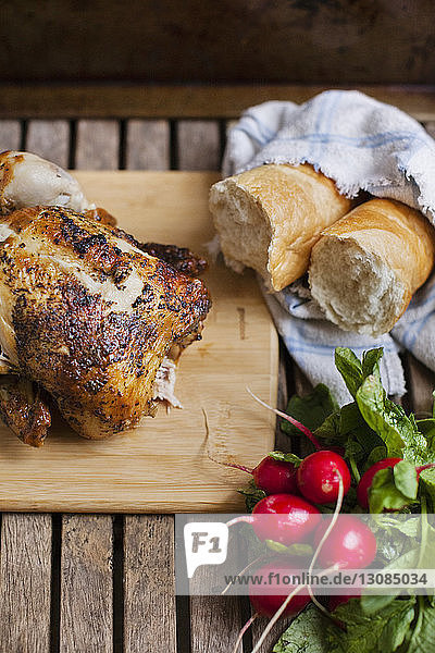 Draufsicht auf gebratenes Huhn mit Radieschen und Brot auf dem Tisch