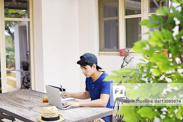 Mann benutzt Laptop beim Lernen am Tisch im Hof